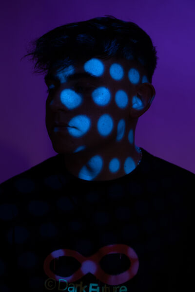 Modeā, purple backdrop with blue dot projection on his face